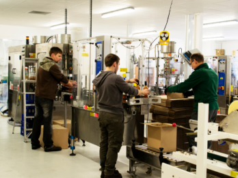 Production line workers at a food and beverage manufacturing facility, packaging bottled goods for shipment