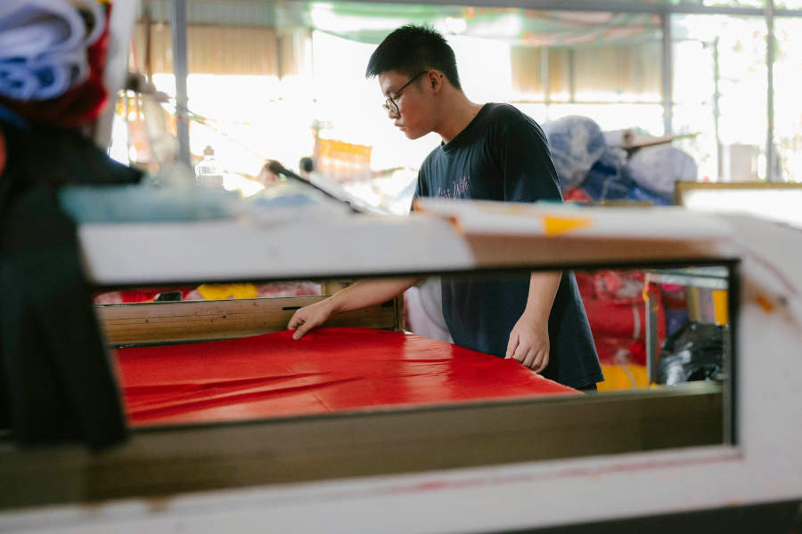Textile mill worker operating a fabric-cutting machine, representative of North Carolina's manufacturing workforce