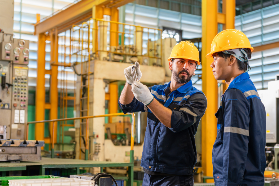 factory workers inspecting a metal part - Language Training Pro factory workers inspecting a metal part